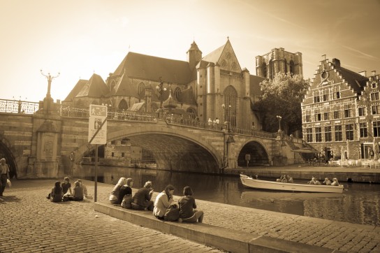People soak up the sun in Front of St Michael's Bridge and Church in Ghent